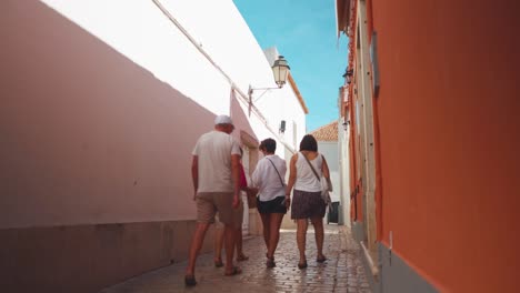 Portugal-Algarve-Loule-Estrecha-Calle-Empedrada-Con-Peatones-Caminando-Al-Sol-De-La-Mañana-4k