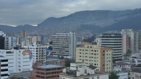 Clouds-blow-over-the-hilly-terrain-surrounding-high-rise-city-buildings-of-Quito-Ecuador-in-morning,-timelapse