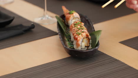 Comer-Rollos-De-Sushi-Tempura-De-Camarones-Con-Palillos-En-Un-Restaurante-Japonés---Cerrar