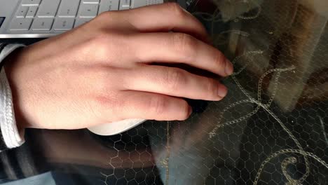 Female-hand-using-a-wireless-computer-mouse-on-top-of-a-glass-table
