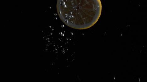 Lemon-Falling-into-Water-Super-Slowmotion,-Black-Background,-lots-of-Air-Bubbles,-4k240fps