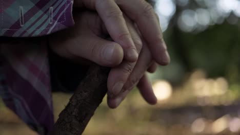 Hands-resting-on-a-wooden-stick-close-up-shot