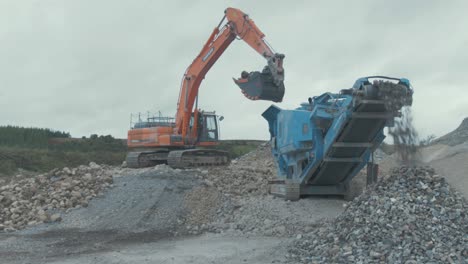 Digger-drops-stone-in-rock-conveyor-at-quarry