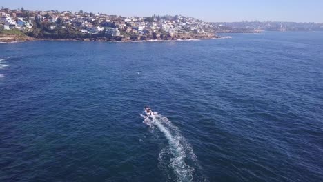 Luftflug-über-Drohne,-Die-Einem-Schnellfischerboot-Am-Küstenstrand-Von-Sydney-Folgt