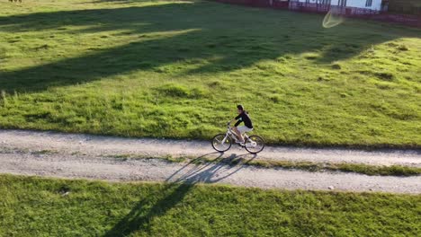Imágenes-Aéreas-De-Un-Hombre-Montando-Su-Bicicleta-En-Una-Carretera-Rural-En-Un-Día-Soleado-De-Verano
