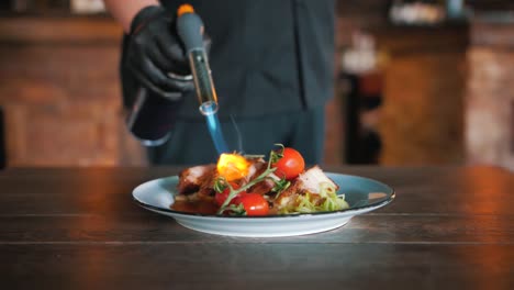 Chef-finishing-a-dish-with-meat-and-tomatos-with-a-Culinary-Torch