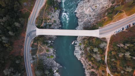 Drone-looking-over-car-bridge-river-crossing-in-Northern-California