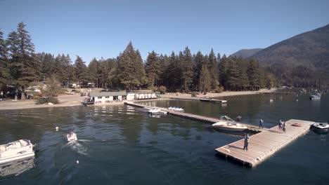 Drone-4K-Footage-of-boat-rental-jet-ski-docked-people-having-leisure-pastime-during-a-sunny-day-clam-Cultus-lake-surrounded-by-mountains-in-Bc-Provincial-park-small-business-travel-economy