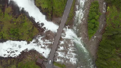 Cars-driving-over-bridge-in-Norwegian-highlands,-Latefossen-Waterfall,-aerial