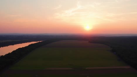 Drone-flies-near-the-Potomac-river-during-a-magnificent-awe-Inspiring-orange-sunset,-aerial,-Maryland-USA