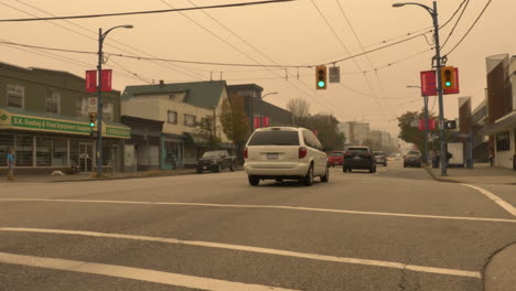 Bodennahe-Aufnahme-Von-Fahrzeugen,-Die-Auf-Der-West-Hastings-Street-In-Vancouver,-BC,-Fahren,-Unter-Dem-Düsteren-Himmel-Aufgrund-Von-Waldbrandrauch-In-Nordamerika