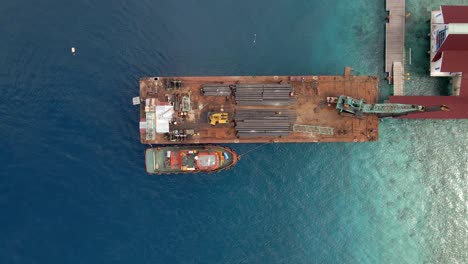 Ascending-aerial-shot-of-industrial-pipe-boat-docking-on-harbor-of-Gili-Trawangan,Asia