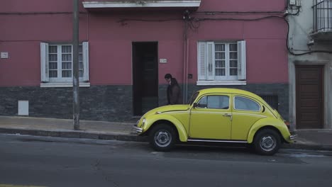Old-VW-Beetle-car-parked,-couple-passing-by