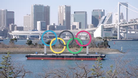 Denkmal-Der-Olympischen-Ringe-In-Odaiba-Mit-Regenbogenbrücke-Und-Der-Skyline-Von-Tokio-Im-Hintergrund-In-Japan