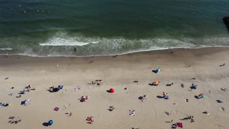 Ein-Blick-Aus-Der-Vogelperspektive-Auf-Menschen,-Die-Sich-An-Einem-Sonnigen-Tag-Am-Strand-Entspannen