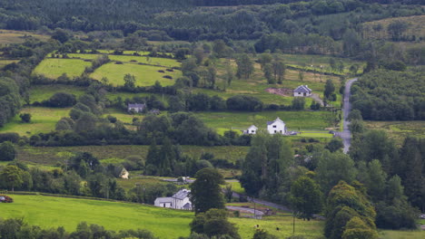 Time-lapse-of-rural-agriculture-landscape-of-green-fields-and-forests-with-farmhouses,-livestock-and-traffic-on-a-cloudy-summer-day-in-Ireland