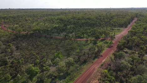 Slow-moving-drone-shot-of-Red-Road-and-Green-Bushland-near-Holmes-Jungle-Nature-Park,-Darwin,-Northern-Territory