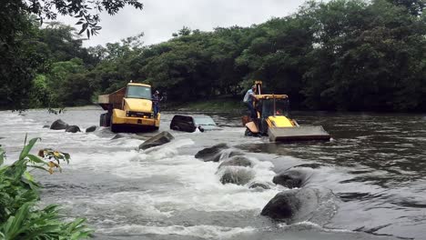 Heavy-Rainfall-and-Flood-Concept,-SUV-Car-Stucked-in-TIdal-River,-Towed-by-Construction-Machines