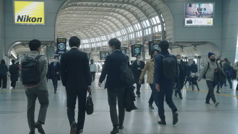 Commuters-In-Masks-Walking-At-Shinagawa-JR-Station-During-Rush-Hour-In-Tokyo,-Japan---wide-shot,-slow-motion