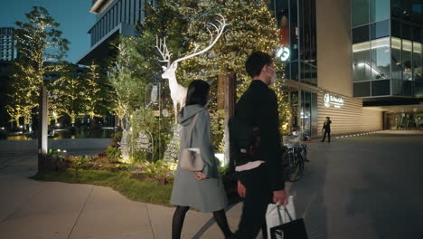 People-Wearing-Masks-Walking-By-Ornamental-Christmas-Tree-And-Reindeer-Outside-A-Building---slow-motion