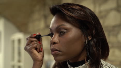 Slowmotion-shot-as-a-model,-black-woman-applying-makeup,-fixing-her-eyelashes