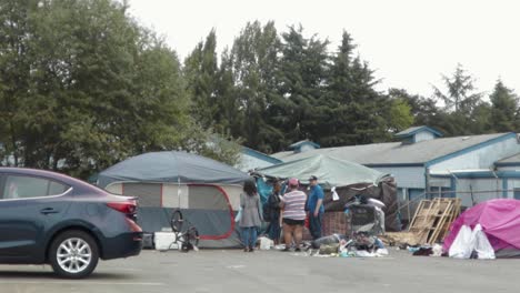 Group-Of-Good-Samaritans-Giving-Donations-And-Help-To-Homeless-People-Living-In-Tent---Covid-19-Social-Outreach---wide-shot
