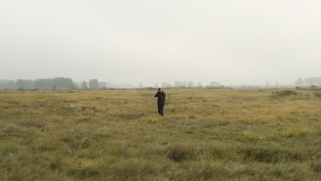 Male-documentarist-taking-pictures-in-a-foggy-grassland,autumn,Czechia