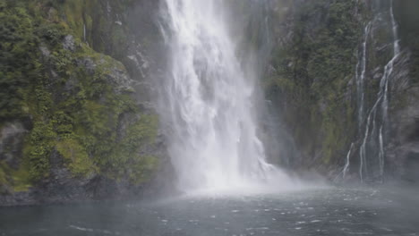 A-thundering-waterfall-crashing-down-the-side-of-a-mountain-on-a-wet-and-rainy-day-in-Milford-Sound,-New-Zealand
