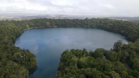 Aerial-drone-video-revealing-a-large-volcanic-crater-lake-fringed-with-a-lush-tropical-rainforest