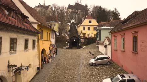 Panoramic-view-of-some-souvenirs-shops-and-the-entrance-of-the-covered-wooden-bridge-in-Sighisoara-with-the-church-on-the-hill-on-background