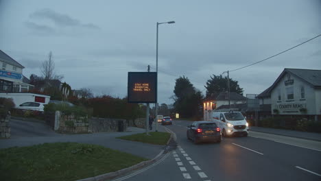 Town-Traffic-in-Early-Evening-Driving-Pass-Signage-Warning-Essential-Travel-Only