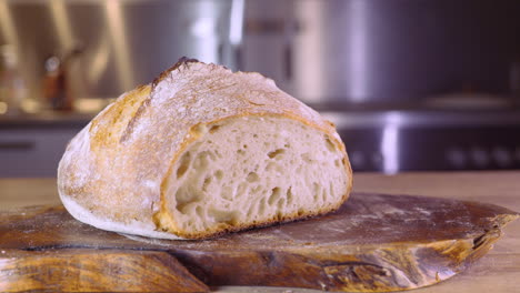 Cut-Loaf-Of-Sourdough-Bread-On-A-Wooden-Board-In-The-Kitchen---pan-shot,-selective-focus