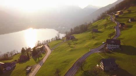 Some-cars-are-driving-on-a-road-in-Amden,-Switzerland-while-sunset