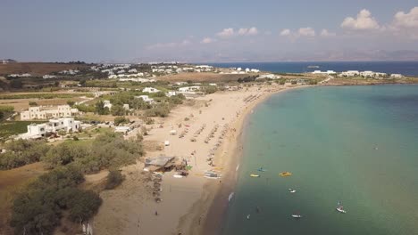 Aufsteigende-Drohnenaufnahme-Von-Touristen,-Die-Den-Goldenen-Sand-Eines-öffentlichen-Strandes-Auf-Der-Griechischen-Insel-Paros-Genießen