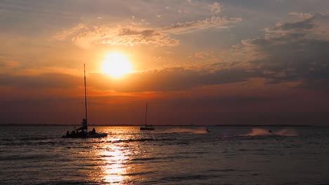 Segelboot-Und-Jetskis-Im-Meerwasser-Bei-Sonnenuntergang