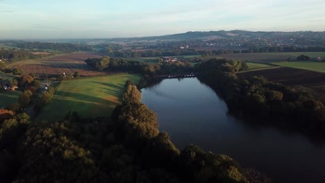 Forward-moving-aerial-over-lake-reservoir-towards-British-countryside---lake-bridge