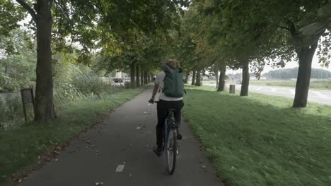 Una-Joven-En-Bicicleta-Por-La-Hermosa-Campiña-Holandesa,-Rodeada-De-árboles