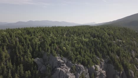 Aerial-Drone-Shot-Flying-Away-From-Mountain-Cliff-And-Forest