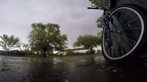 Bicicleta-Apoyada-Contra-Una-Valla-De-Madera-Azul-En-El-Camino-De-Entrada-De-Una-Casa-En-Un-Día-Lluvioso