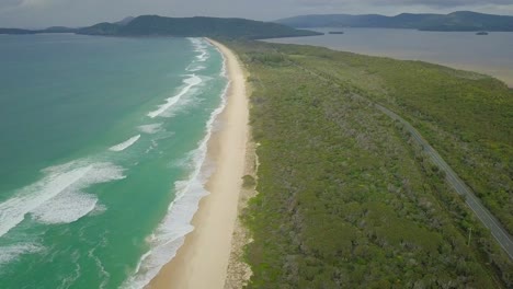 Beautiful-aerial-flight-over-beach-road-along-wild-blue-ocean,-Australia