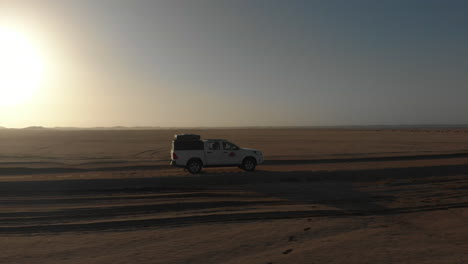Horizontal-panning-shot-following-vehicle-across-flat-desert