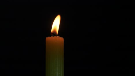 A-single-candle-flickering-in-a-breeze-with-a-black-background-and-close-up
