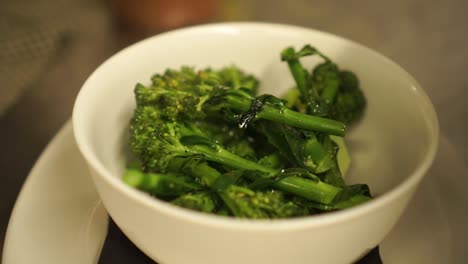 Close-Up---Putting-steamed-green-fresh-broccoli-into-a-white-bowl