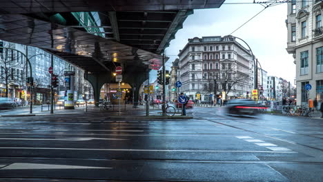 Berlin-crossroad-with-fast-moving-people-and-vehicles-on-a-rainy-day---4k