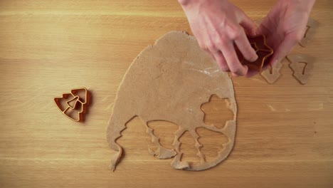 Making-christmas-shapes-from-gingerbread-dough-on-a-wooden-table-topdown-video