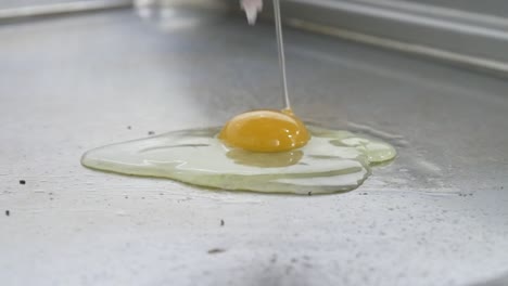 An-egg-is-cracked-and-dropped-into-a-restaurant-grill-by-a-gloved-hand