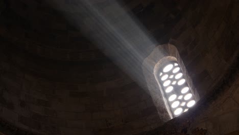 Nahaufnahme-Eines-Hellen-Lichts,-Das-Durch-Ein-Altes-Kirchenfenster-Scheint-Und-Durch-Die-Dunkelheit-Der-Kathedrale-Strahlt