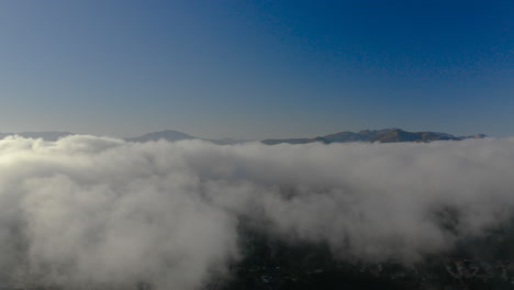Aerial-view-of-low-fog-over-mountains-in-San-Diego-during-sunrise