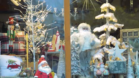Santa-Claus,-Luces-Navideñas-Y-Decoraciones-Detrás-De-La-Ventana-De-La-Tienda-De-La-Ciudad