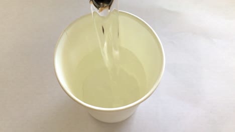 white-paper-cup-getting-filled-with-water,-making-coffee,-primitive